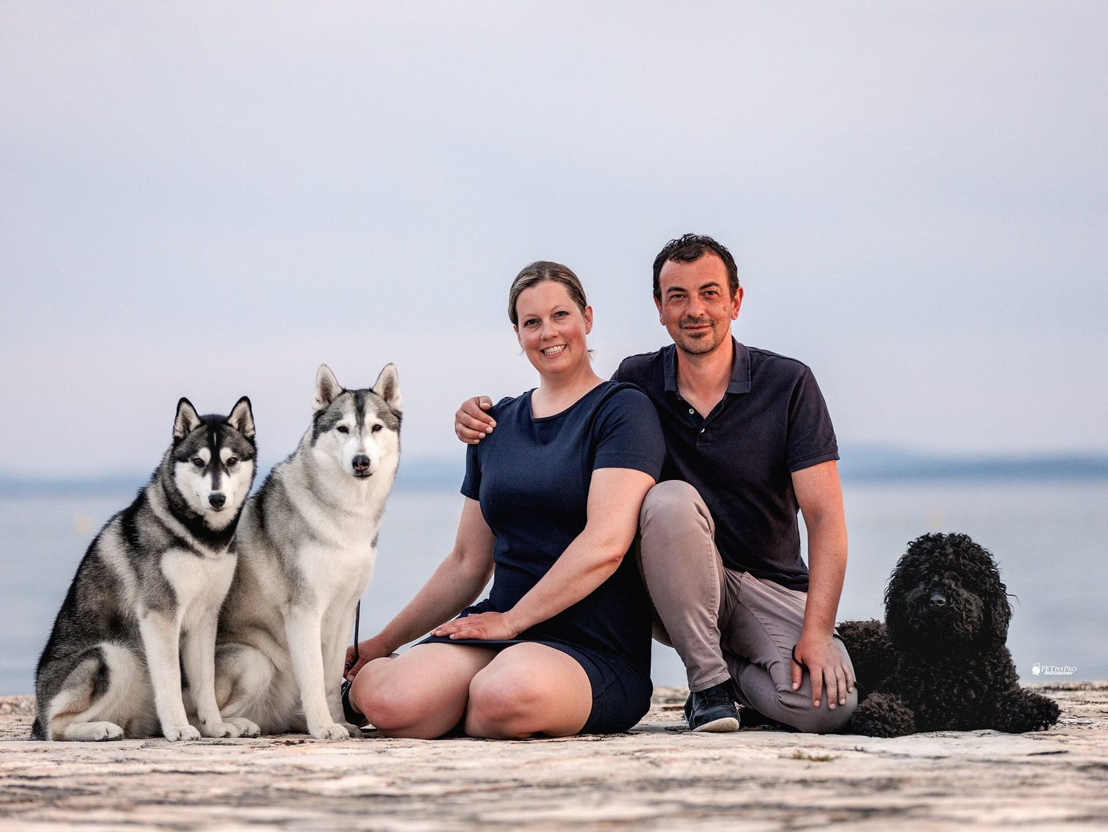 Das Züchterpaar von Joiel’s Palace mit zwei Siberian Huskys und dem Barbet am Meer